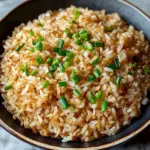 Plate of crispy coconut rice garnished with herbs, showcasing its texture and flavor.