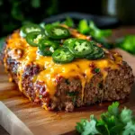 Keto Jalapeño Cheddar Meatloaf served on a plate, garnished with herbs.