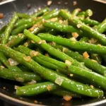 Plate of simple sautéed green beans seasoned and ready to serve.