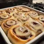 Delicious and fluffy cinnamon rolls with cream cheese frosting on a wooden table.