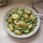 Creamy green bean potato salad with fresh ingredients in a bowl