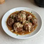 Crock Pot French Onion Meatballs served in a bowl with melted cheese