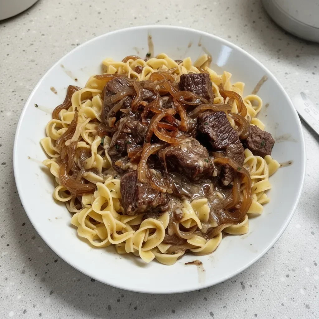 Delicious bowl of French onion beef and noodles with melted cheese and herbs