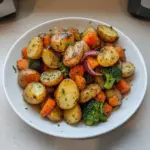 Garlic herb roasted potatoes with colorful roasted vegetables on a serving tray.