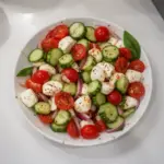 Cucumber Caprese Salad with tomatoes, mozzarella, and basil on a plate