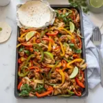 Sheet pan meal featuring colorful chicken fajitas with peppers and onions.