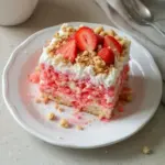 Delicious strawberry crunch poke cake topped with crushed strawberries and whipped cream
