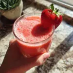 Fresh strawberry lemon smoothie in a glass with a straw and mint leaves