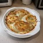 Plate of cheesy baked onions, a delicious Tennessee dish garnished with herbs.