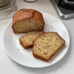 Vegan Banana Bread loaf with ripe bananas and walnuts on a wooden cutting board