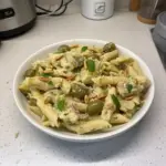 Plate of Artichoke Pasta garnished with fresh herbs and parmesan cheese