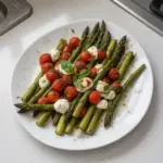 Plate of Caprese Roasted Asparagus drizzled with balsamic glaze and topped with mozzarella.