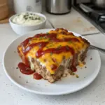 Cheesy Meatloaf Casserole served with melted cheese and herbs on top