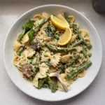 A bowl of creamy lemon asparagus pasta garnished with herbs