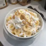 Easy banana pudding fluff salad in a glass bowl with whipped cream and bananas