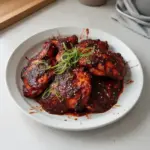 Delicious plate of Gochujang Chicken garnished with green onions and sesame seeds.