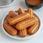 Healthy baked churro bites coated in cinnamon sugar served on a plate.