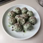 Mint Chocolate Chip Protein Balls recipe with mint leaves and chocolate chips.