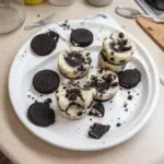 Oreo Cheesecake Bites arranged on a plate, topped with crushed Oreos.