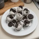 Oreo no-bake cheesecake cups topped with crushed Oreos and chocolate drizzle.
