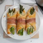 Prosciutto asparagus puff pastry bundles served on a plate