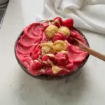 Thick strawberry smoothie bowl topped with fruits and seeds, no banana included.