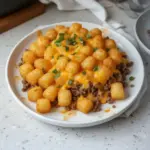 Tater tot casserole with ground beef, cheese, and vegetables in a baking dish.