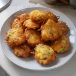 Plate of crispy vegetable fritters garnished with fresh herbs