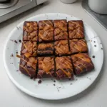 Delicious Biscoff brownies topped with drizzle and cookie crumbs