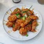 Delicious plate of Chinese honey garlic chicken garnished with green onions