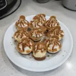Cookie butter cheesecake cups topped with a drizzle of cookie butter and crushed cookies