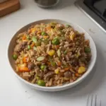 Delicious bowl of ground venison fried rice garnished with vegetables.