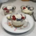 Healthy protein cheesecake jars topped with fresh berries and a dusting of cocoa