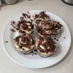 Delicious loaded brownie cheesecake cups topped with chocolate and cream.