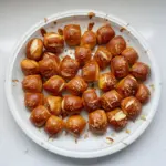 A bowl of warm, golden pretzel bites served with dipping sauces.