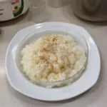 Bowl of creamy homemade tapioca pudding garnished with fruits and coconut flakes.