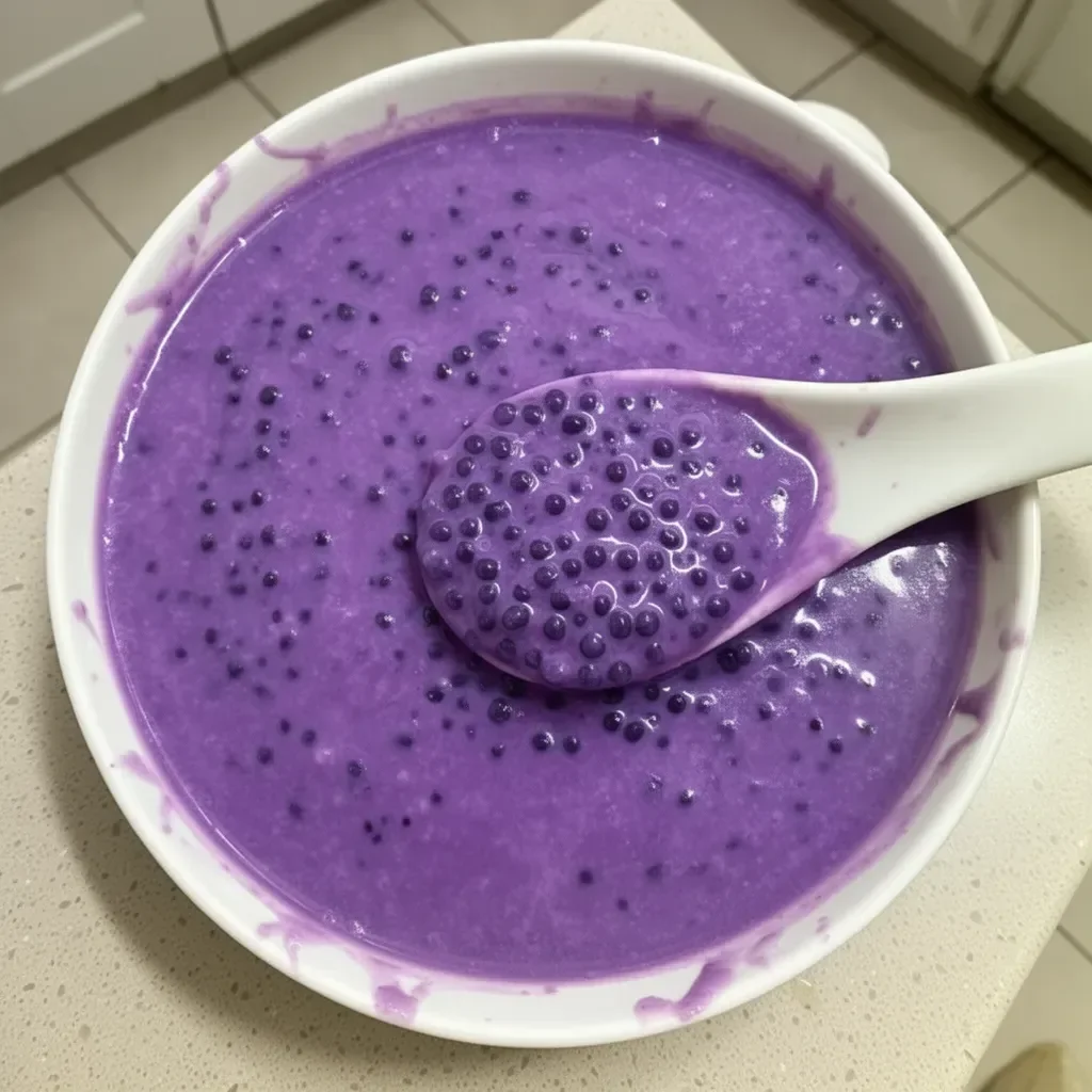 A bowl of purple yam sago dessert topped with coconut and colorful toppings.